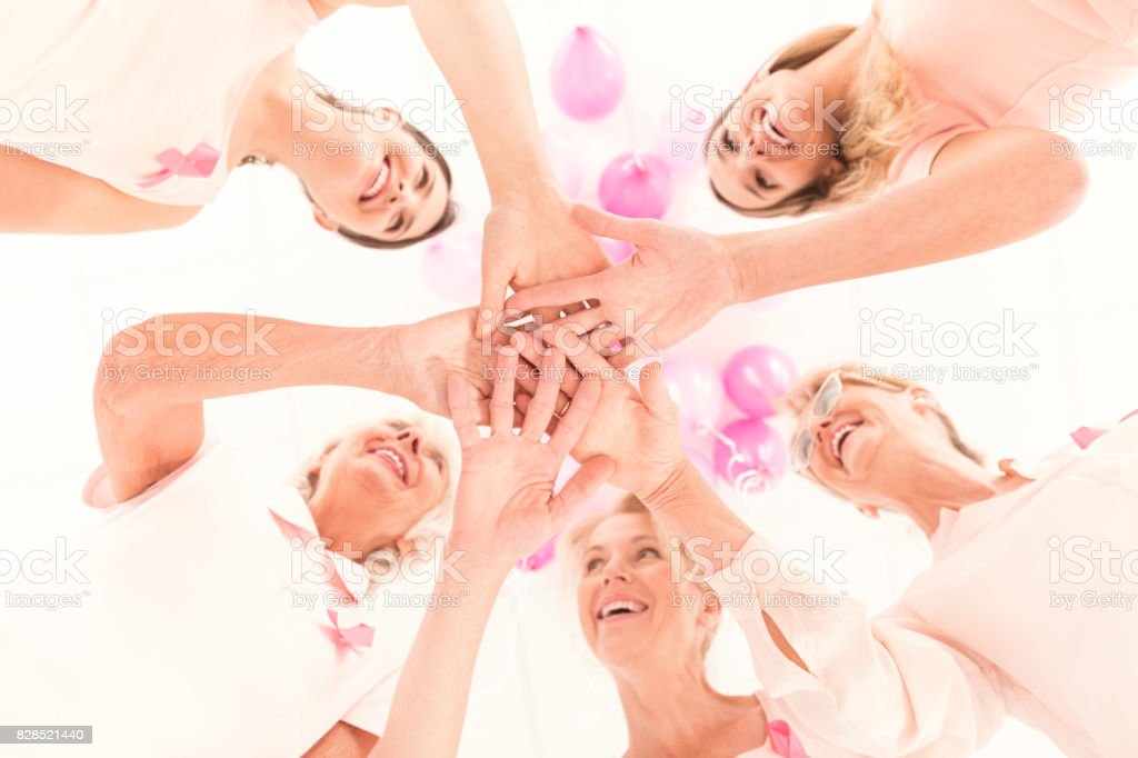 Team of happy smiling women with pink ribbons